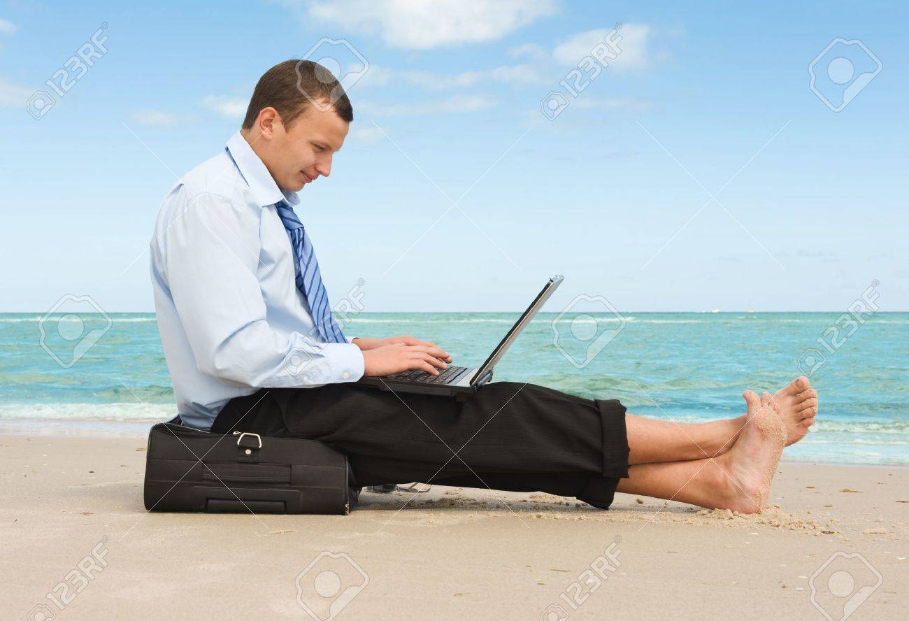 13195045-young-businessman-working-with-laptop-on-the-beach--Stock-Photo.jpg